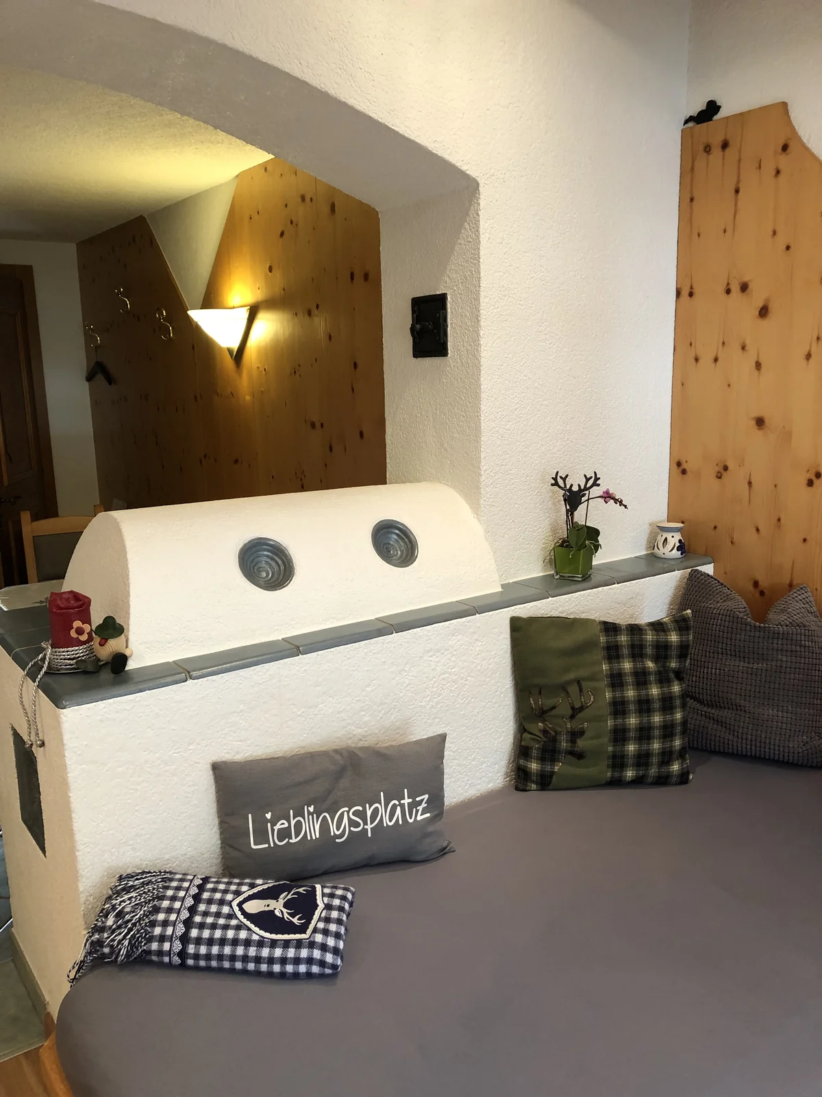 Gemütliche Ofenbank mit Couch, Kissen und Tiroler Holzvertäfelung